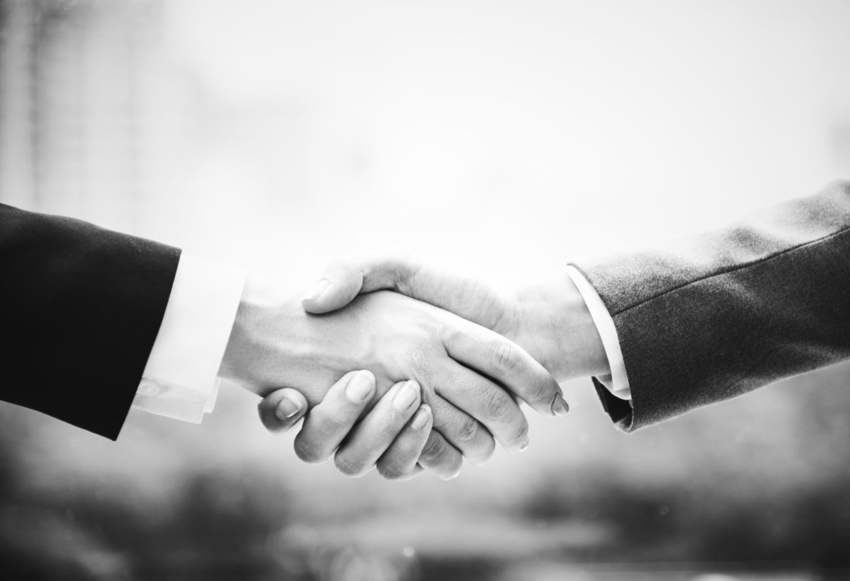 A black and white close up photo of two business people shaking hands.